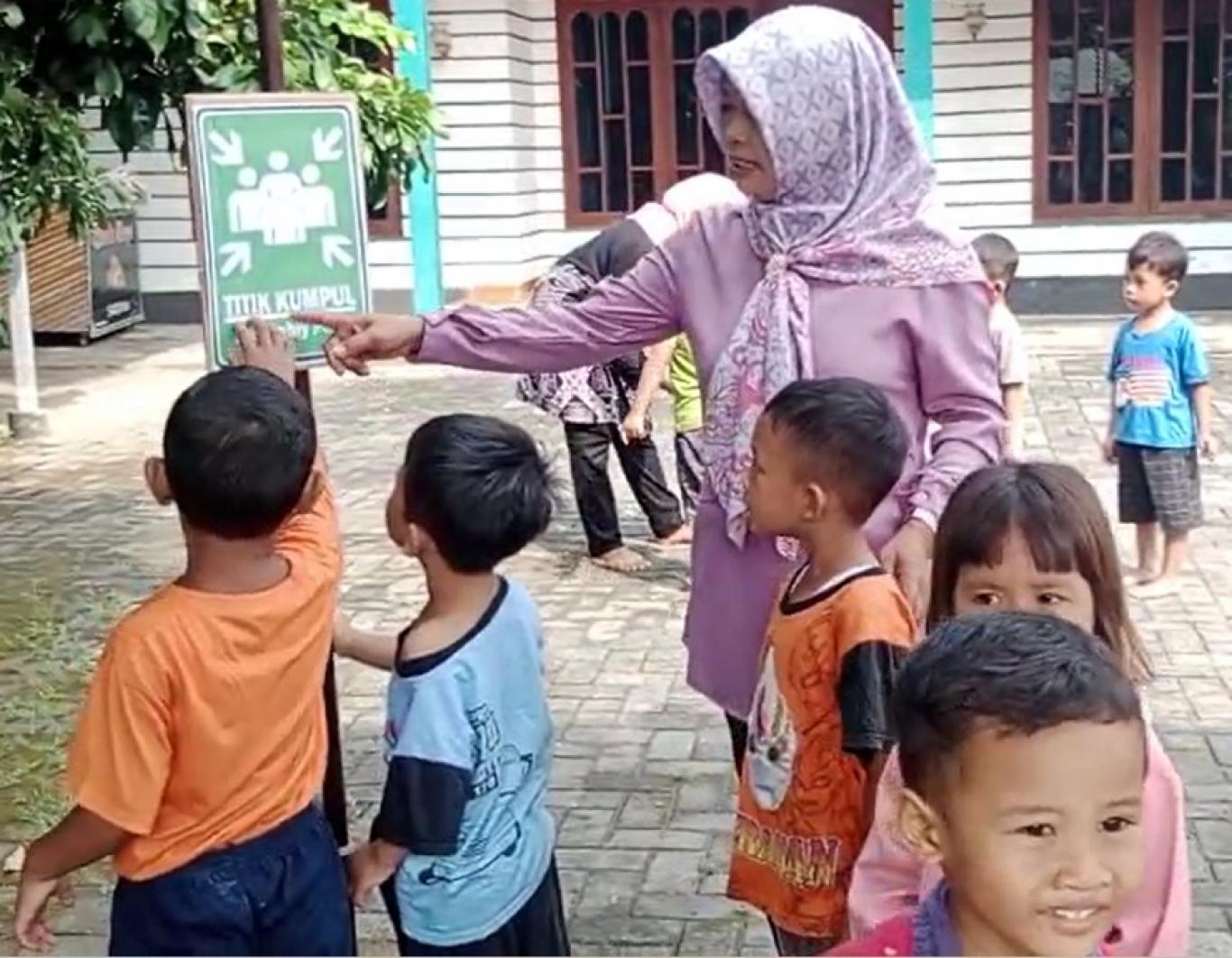 Pendidik menunjukkan tanda titik kumpul kepada anak-anak KB Anggrek Bulan